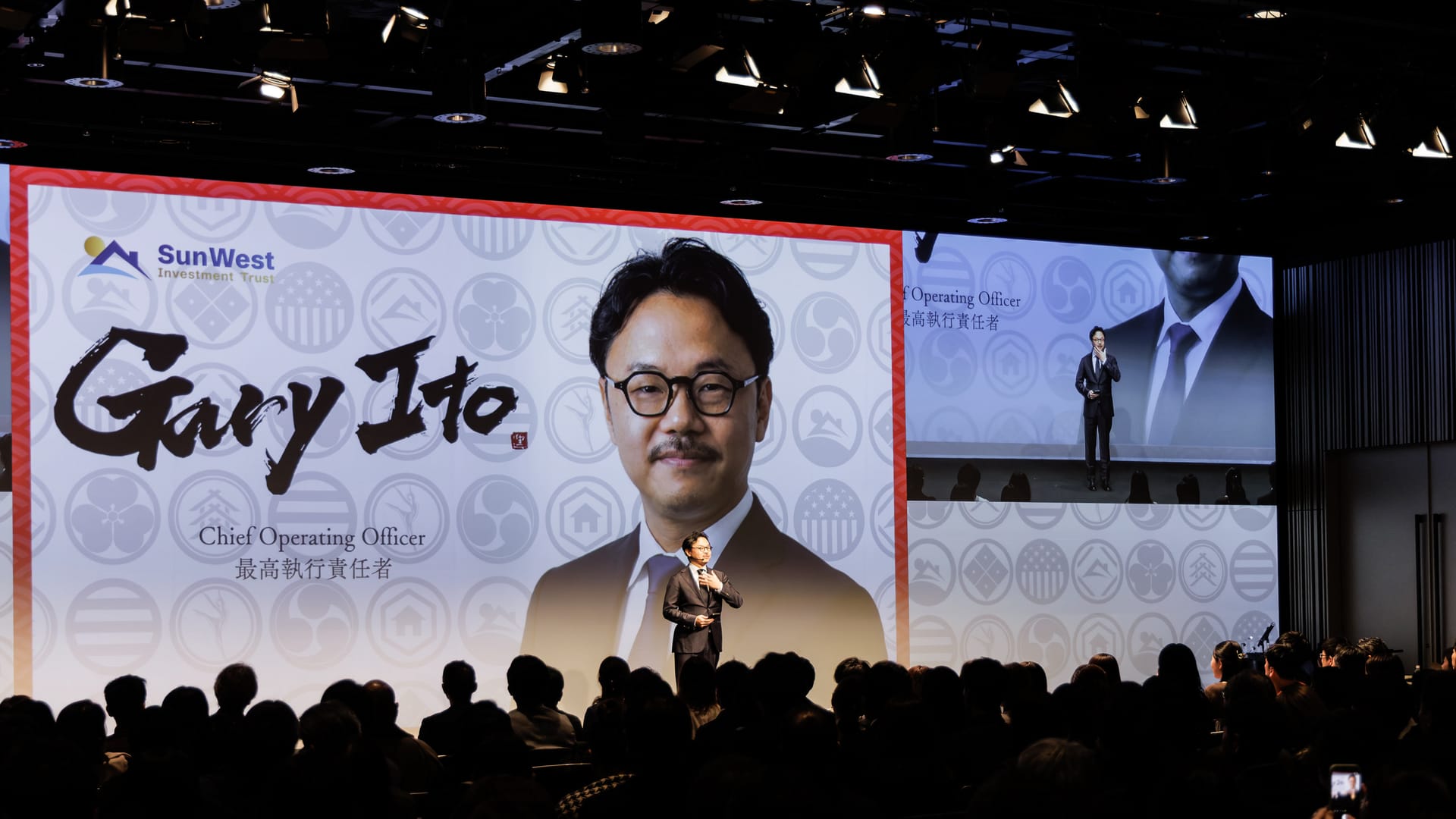Gary Ito 氏の紹介スライドと、スマートフォンを掲げる来場者